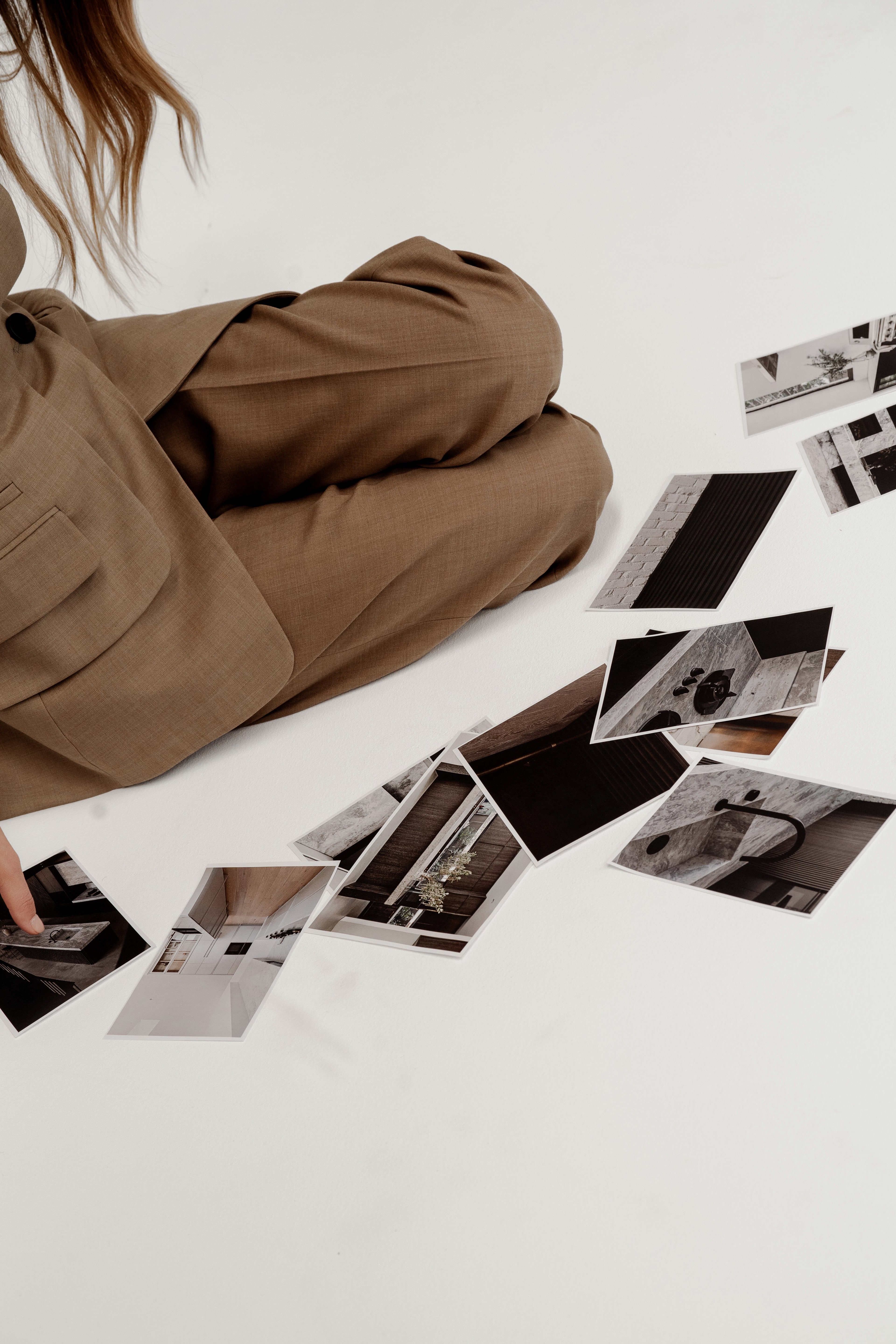 A man in black and a blonde woman in a white shirt pin interior design reference photos to a large studio mood board wall.
